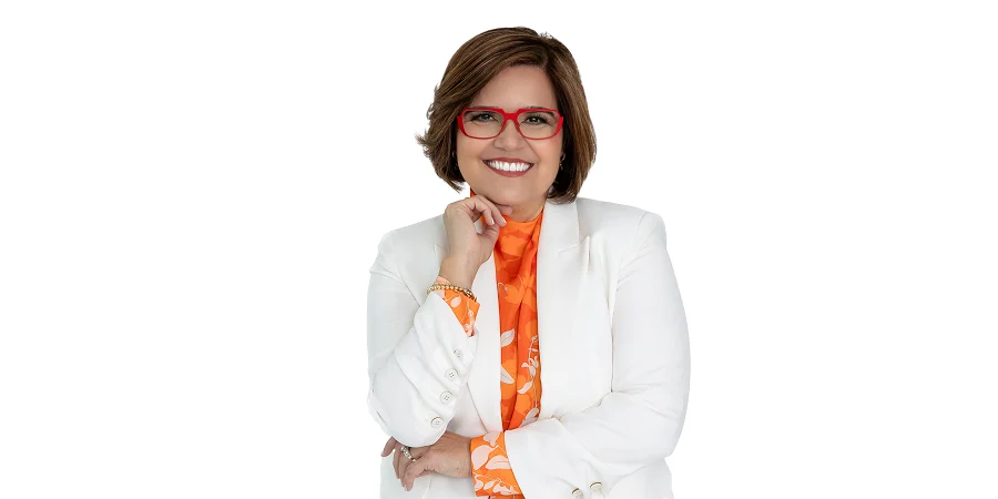 Joni Marmo smiling in a white blazer and orange blouse, exuding warmth and confidence as a Christian motivational speaker.